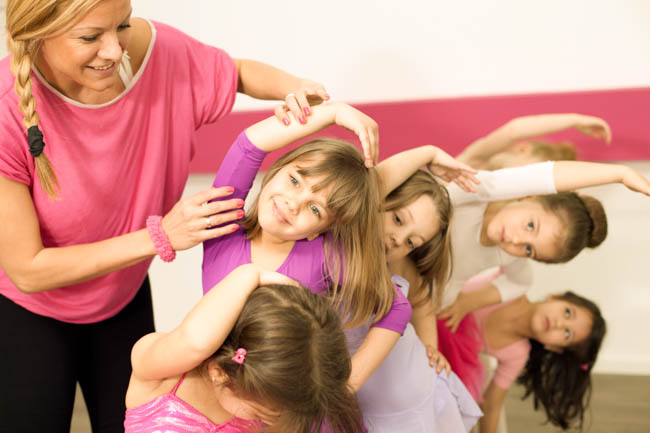 little girls in dance class, instructor helps dancers