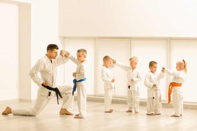 teaching children martial arts, little children with instructor practicing karate in dojo